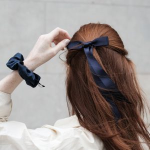 Rothaarige Frau von hinten mit dunkelblauer Haarschleife und dunkelblauem Scrunchie am Handgelenk